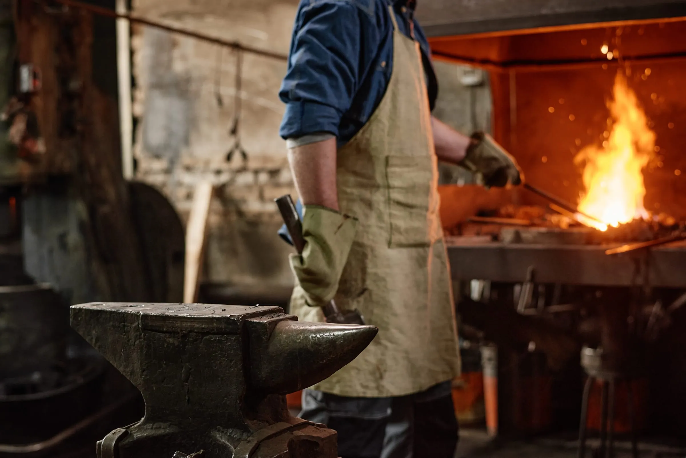 Blacksmith in a leather apron beside the forge fire